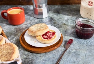 Gluten-Free Sourdough English Muffins made with Bread Flour sliced on a plate with butter and jam
